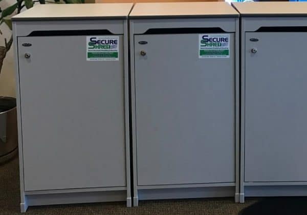 Indianapolis document shredding services image shows 3 Secure Shred containers lined up in a row. They are gray.