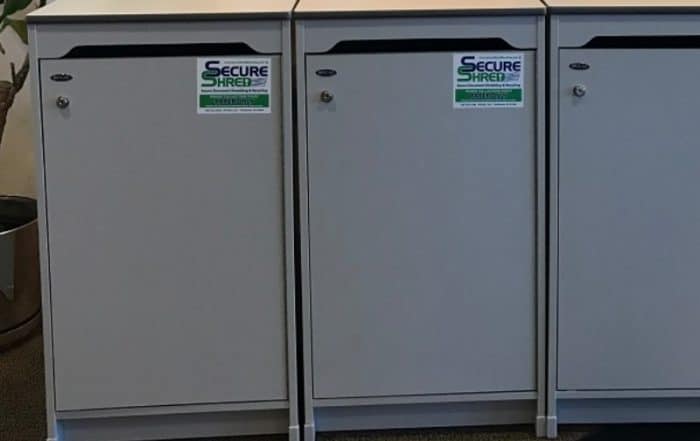 Indianapolis document shredding services image shows 3 Secure Shred containers lined up in a row. They are gray.